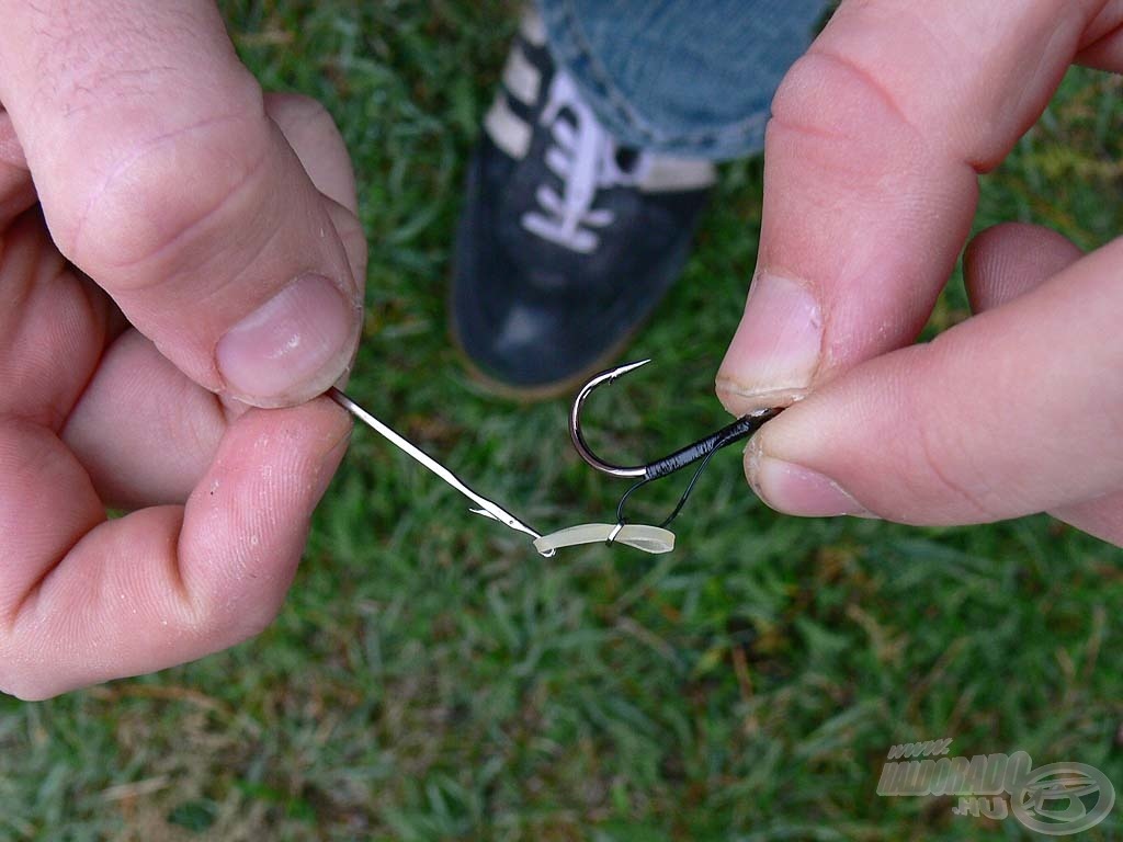 Első lépésként a gumigyűrűt húzzuk át félig a fémkarikán egy fűzőtű segítségével